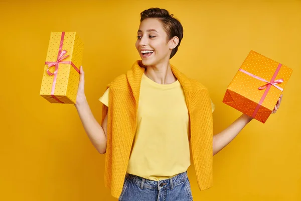 Szczęśliwa Młoda Kobieta Niesie Dwa Pudełka Prezentów Stojąc Żółtym Tle — Zdjęcie stockowe