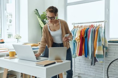 Confident young woman working in fashion store office