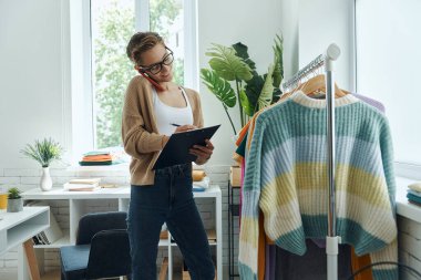 Moda mağazasında çalışırken not defteri kullanan güzel bir genç kadın.