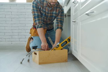 Kendine güvenen tamirciye yakın çekim Mutfak lavabosunu tamir etmek için gerekli aletleri hazırlıyor