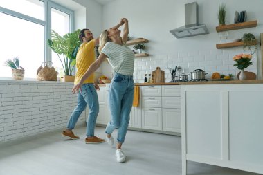 Full length of playful couple dancing at the domestic kitchen