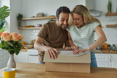 Neşeli genç çift evdeki mutfakta dururken kutuları açıyor.