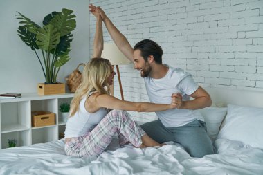 Mutlu genç çift yatakta birlikte eğleniyor.