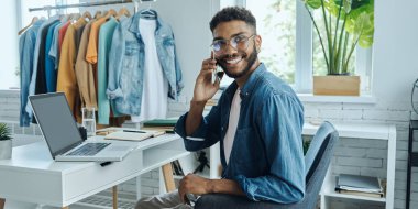 Moda mağazasında otururken cep telefonuyla konuşan kendinden emin bir Afrikalı.