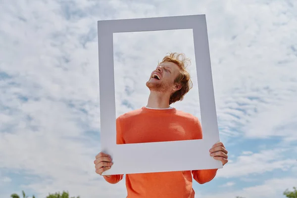 Relaxed Young Redhead Man Looking Picture Frame Smiling While Standing — Photo