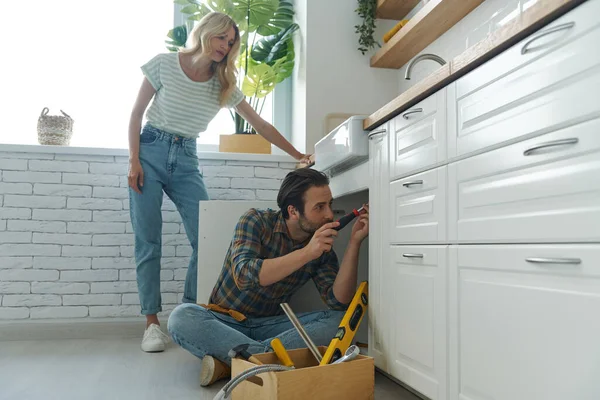 Confident Young Man Repairing Sink While Woman Standing Domestic Kitchen — Stockfoto