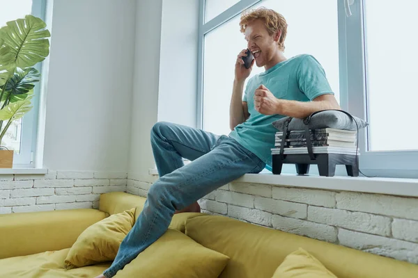 Bonito Ruivo Homem Falando Telefone Celular Enquanto Sentado Peitoril Janela — Fotografia de Stock