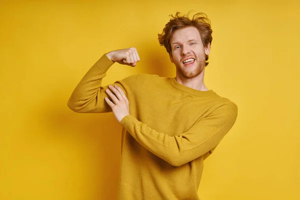 Playful Redhead Man Touching His Bicep While Standing Yellow Background — ストック写真