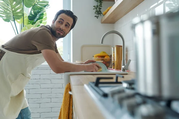 Bored Young Man Washing Dishes Domestic Kitchen Looking Shoulder — Foto Stock