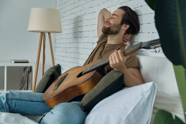 Handsome Young Man Holding Acoustic Guitar While Relaxing Bed Home — Zdjęcie stockowe
