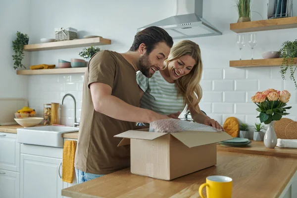 Happy Young Couple Unpacking Box Smiling While Standing Domestic Kitchen — Fotografia de Stock