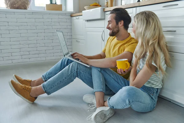 Beautiful Young Couple Using Laptop While Sitting Floor Leaning Kitchen — Fotografia de Stock