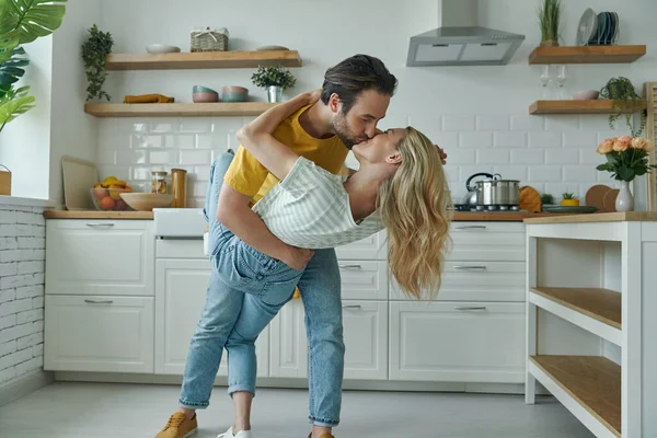 Genç ve güzel bir çift evcil mutfakta dans edip öpüşüyor.