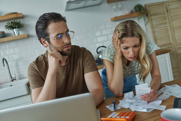 Frustrated young couple calculating finances at the domestic kitchen