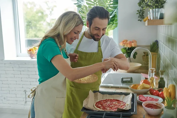 Pareja Feliz Rociando Queso Rallado Pizza Mientras Cocinan Juntos Cocina —  Fotos de Stock