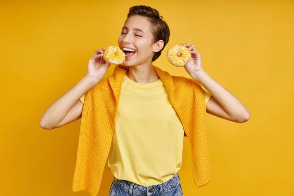 Игривая Молодая Женщина Пробует Пончики Стоя Желтом Фоне — стоковое фото