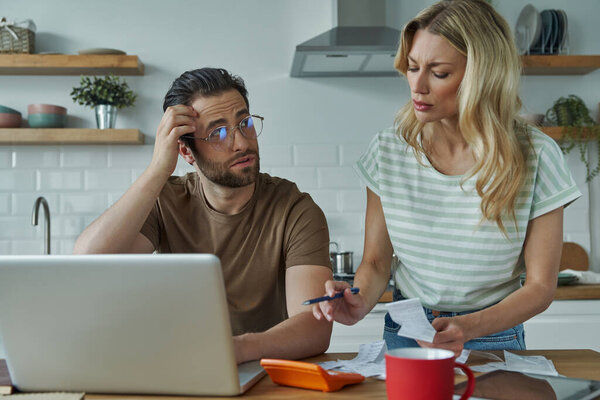 Young couple going over financial bills while sitting at the domestic kitchen