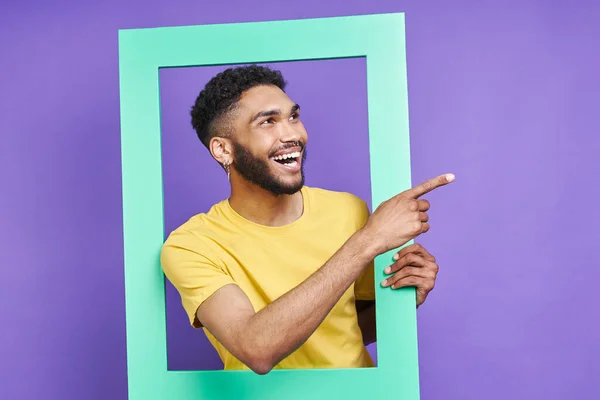 Happy African Man Looking Picture Frame Pointing Away Purple Background —  Fotos de Stock