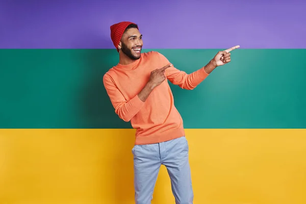 Handsome African Man Pointing Away Smiling While Standing Colorful Background — ストック写真