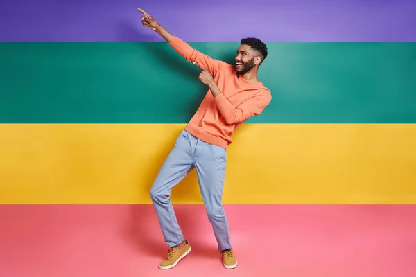 Full Length Playful African Man Pointing Away While Standing Colorful — Stockfoto