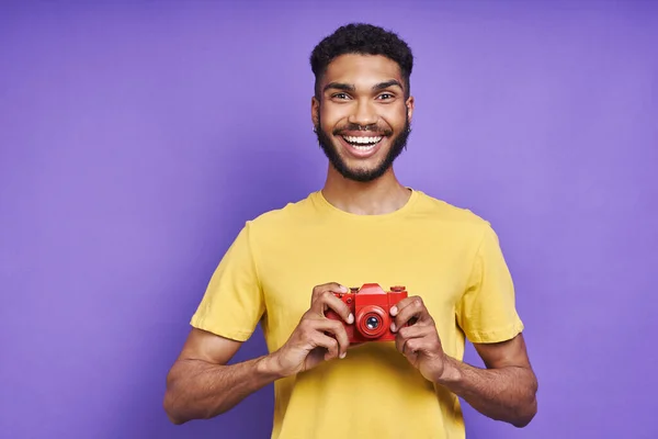 Young African Man Holding Photo Camera Smiling While Standing Purple — Zdjęcie stockowe