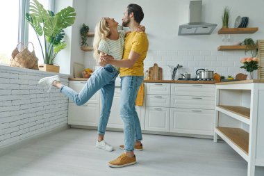 Evcil mutfakta dans eden neşeli genç bir çift.