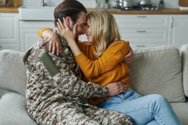 Young man in military form hugging his wife after coming home from war