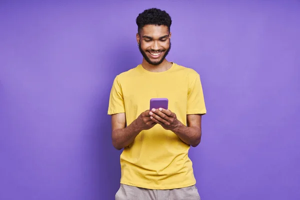 Handsome African Man Using Smart Phone Smiling While Standing Purple — Zdjęcie stockowe