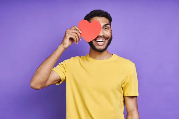 Playful African Man Covering His Eye Paper Heart While Standing — Stok fotoğraf