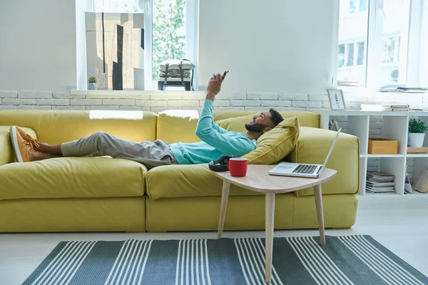 Carefree African Man Using Smart Phone While Relaxing Couch Home — Stok fotoğraf