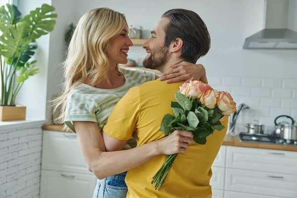 Cheerful Young Man Surprises His Girlfriend Bunch Flowers Kitchen — Fotografia de Stock