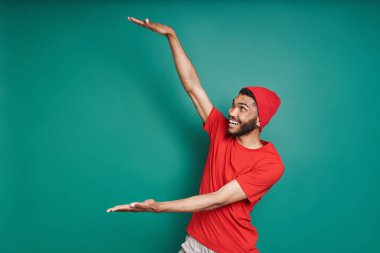 Yakışıklı Afrikalı adam yeşil arka planda dururken uzun boylu ve gülümsüyor.