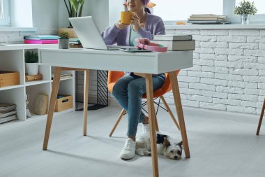 Close-up of woman enjoying hot drink while sitting at her working place
