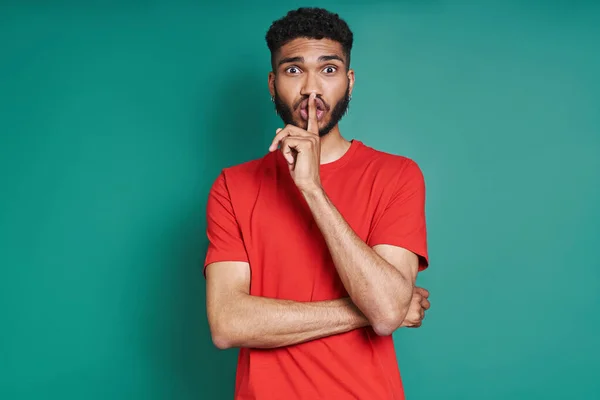 Young African Man Holding Finger Lips While Standing Green Background —  Fotos de Stock