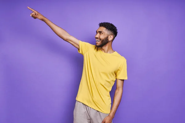 Szczęśliwy Afrykanin Wskazując Daleko Stojąc Fioletowym Tle — Zdjęcie stockowe