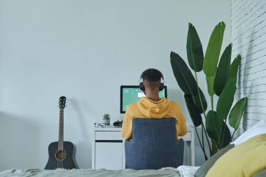 Rear view of African man using computer while sitting at his working place at home