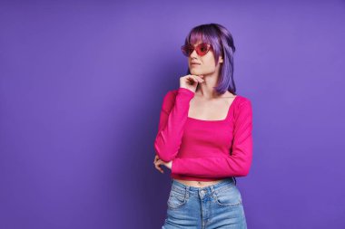 Mor arka planda dururken el ele tutuşan düşünceli genç bir kadın.