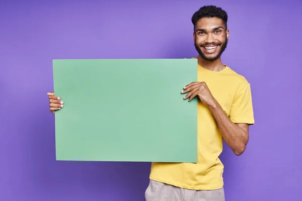 Веселый Африканский Мужчина Держит Зеленое Знамя Стоя Фиолетовом Фоне — стоковое фото