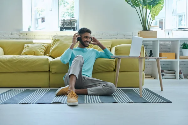 Cheerful African Man Headphones Using Laptop While Sitting Floor Home — Stockfoto