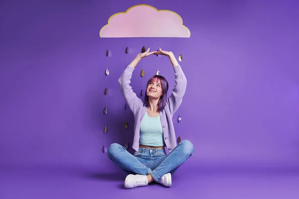 Cheerful Young Woman Sitting Paper Cloud Smiling Purple Background — Zdjęcie stockowe