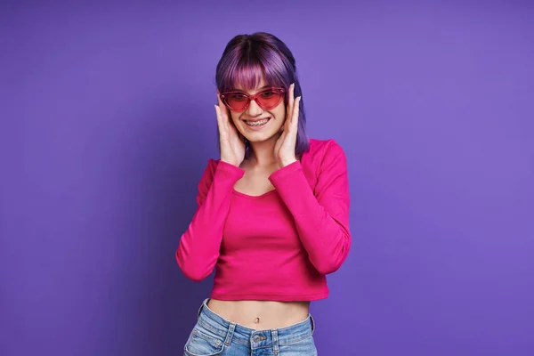 Cheerful Young Woman Adjusting Eyeglasses While Standing Purple Background — 스톡 사진