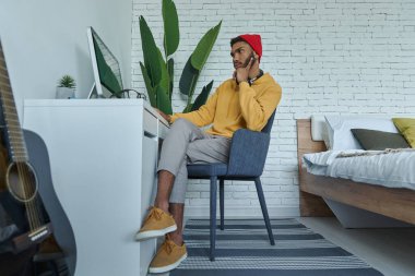 Genç Afrikalı adam evinde çalışırken bilgisayar kullanıyor.