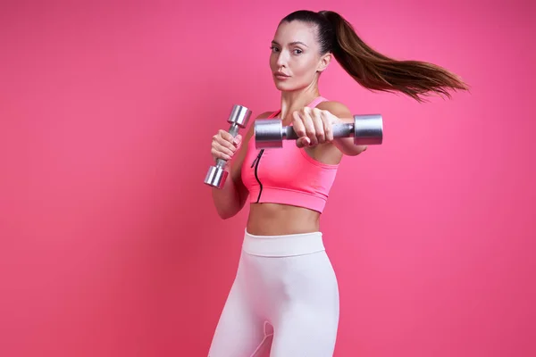 Confident Young Woman Sports Clothing Exercising Dumbbells Pink Background — Stockfoto