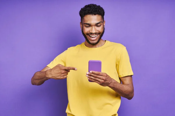 Cheerful African Man Pointing His Smart Phone While Standing Purple — Stockfoto