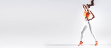 Confident young woman in sports clothing adjusting her hair against white background