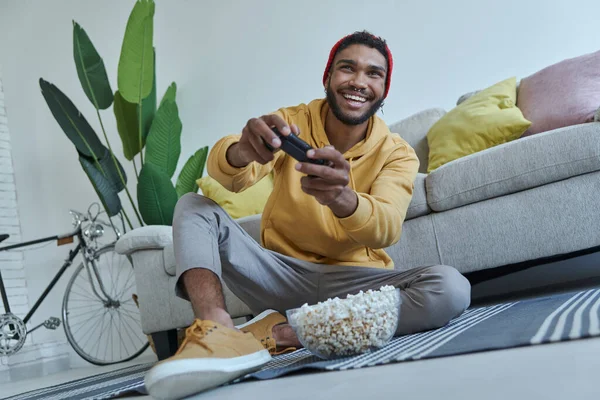 Happy Young African Man Playing Video Games While Sitting Floor — ストック写真