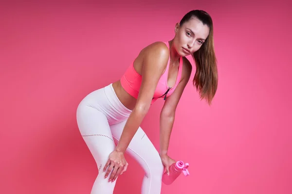 Relaxed Young Woman Leaning Knees While Standing Pink Background — Zdjęcie stockowe