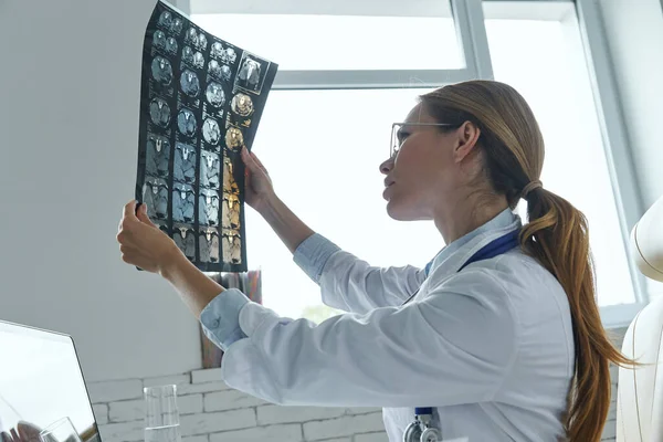 Female Doctor Examining Medical Ray While Sitting Office — Photo