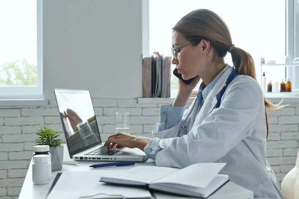 Médica Feminina Confiante Falando Telefone Usando Computador Enquanto Está Sentada — Fotografia de Stock