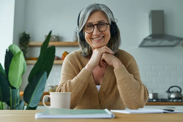 Senior Woman Headphones Having Web Conference While Sitting Domestic Kitchen — Φωτογραφία Αρχείου